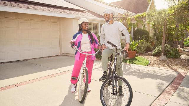A man and a woman sitting on bicycles in a driveway