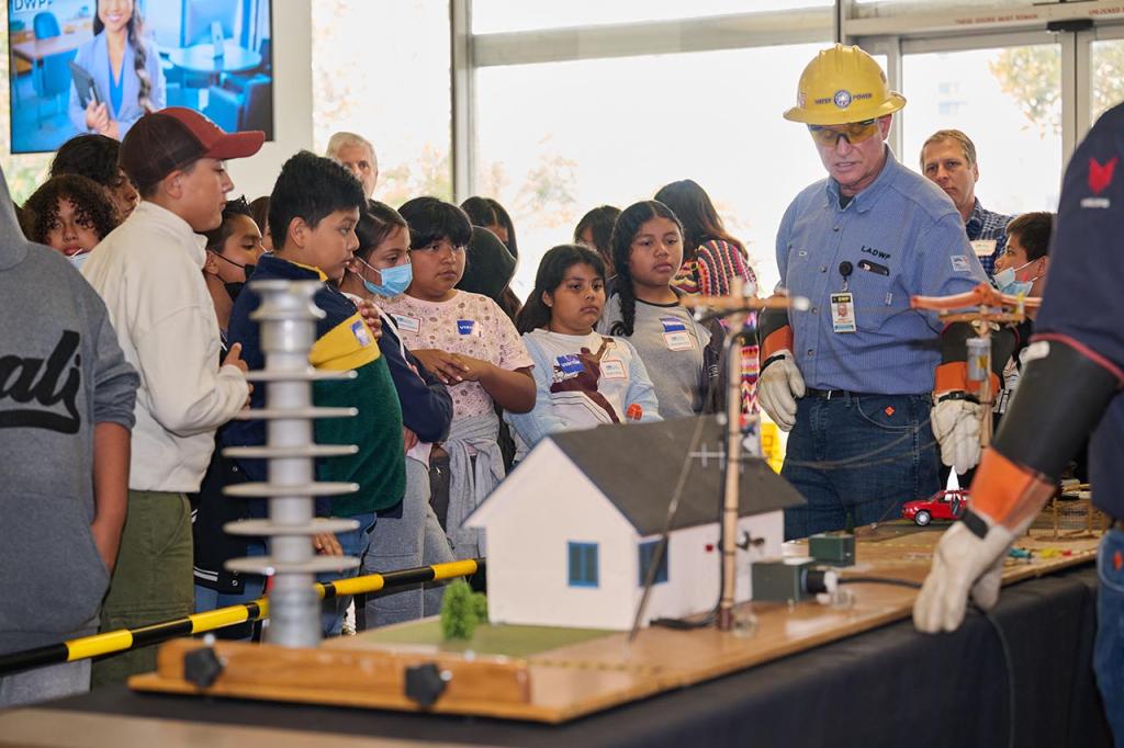 LADWP employee speaking in front of kids with model house display