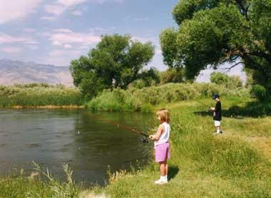 Two kids fishing at edge of lake