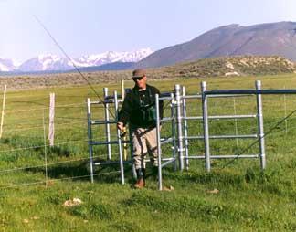 Fisherman walking through gate door of metal fence in grace field.