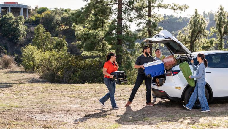 four friends  loading picnic equipment into an EV