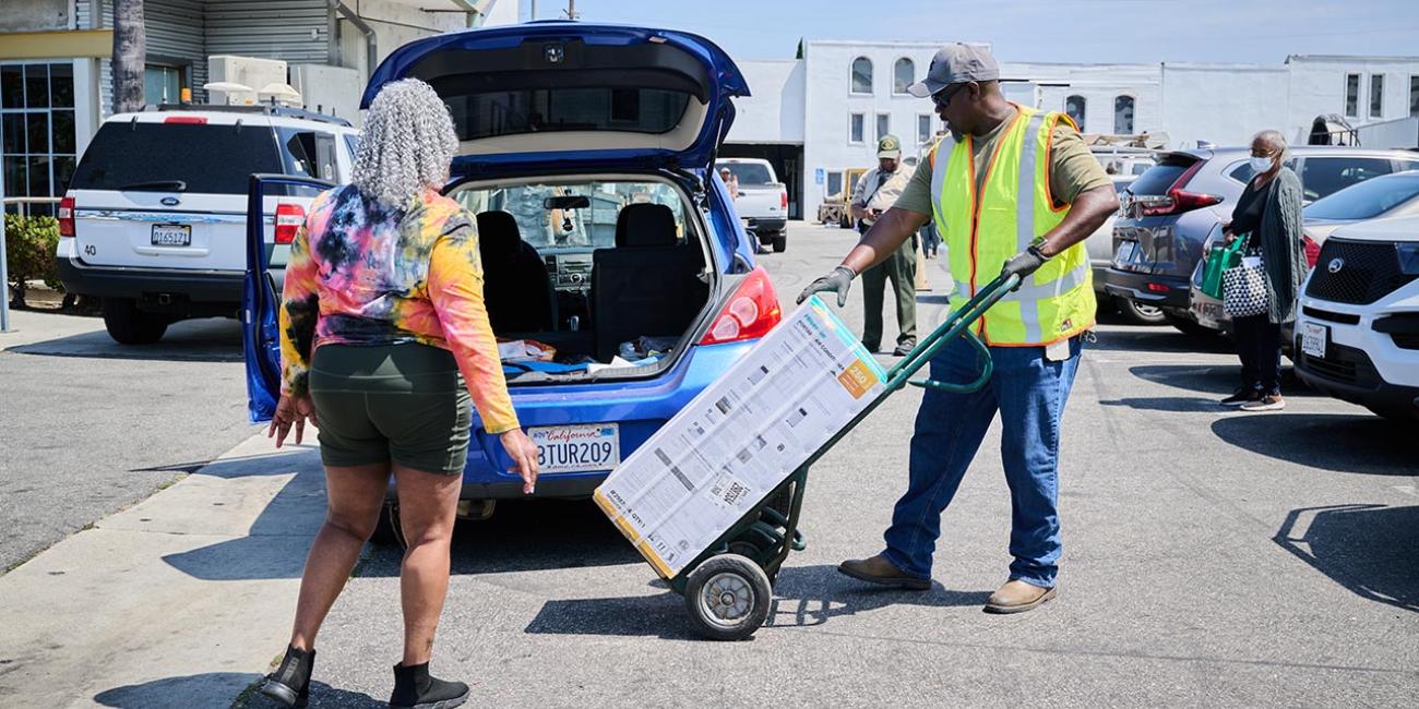 LADWP staff helps load AC unit into car at Watts event July 15, 2024.