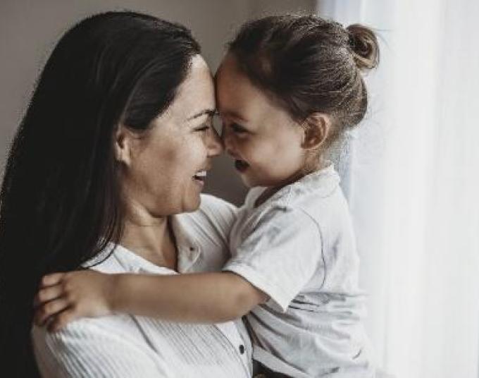 Smiling woman is carrying a smiling child. 