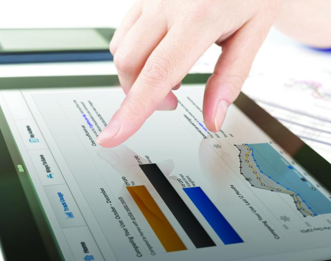 Hand scrolling a screen tablet showing chart and graphs.