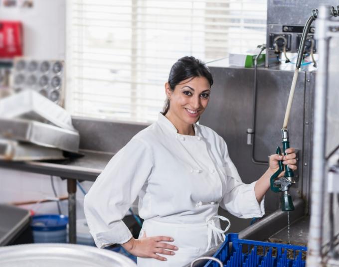 A kitchen worker washes dishes.