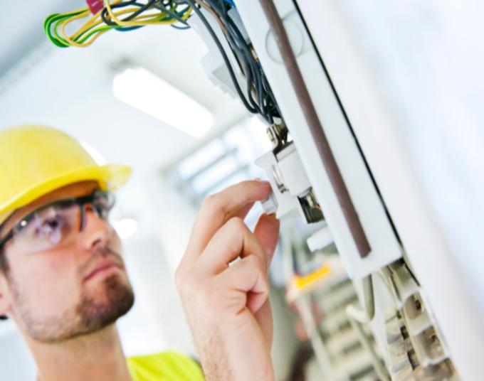 A man in a hard hat twists a knob.