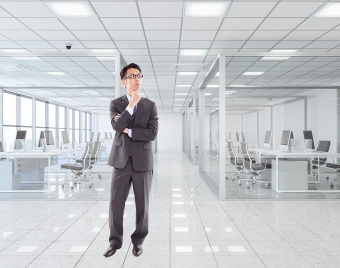 A man in a suit looks pensive in a well-lit office.