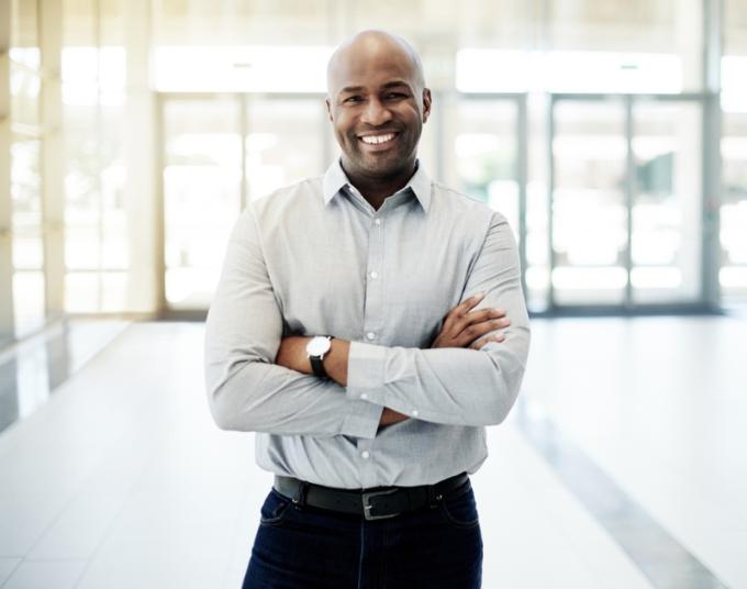 A businessman smiles in a well-lit business.