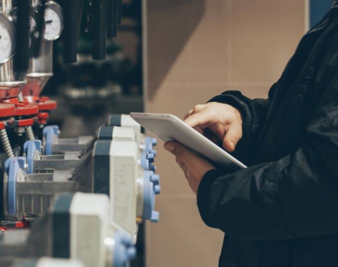 A person uses a tablet while looking at water meters.