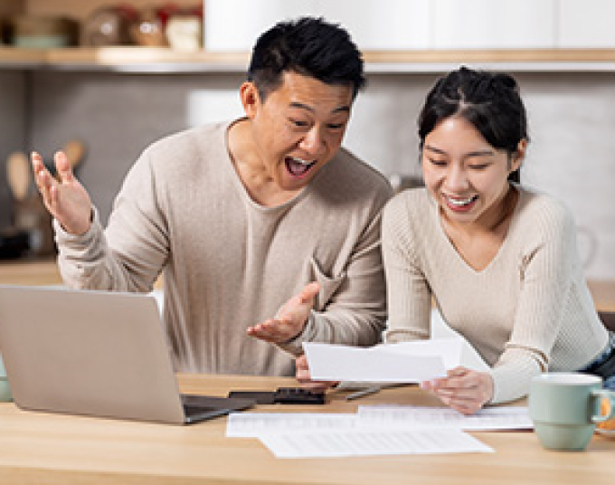 Man and woman looking at utility bill with excitement.