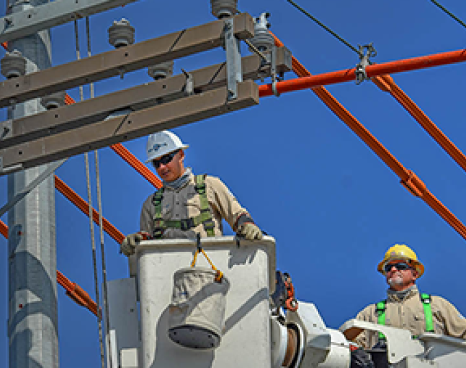 Two men working in a bucket truck to fix power lines.