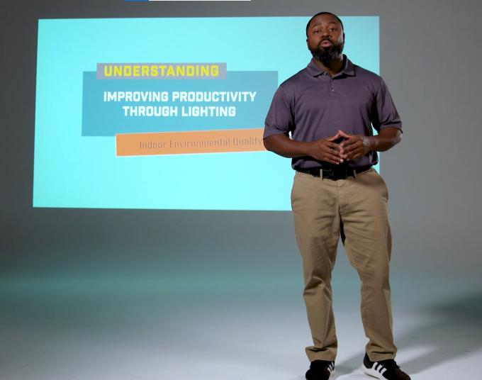 Man stands in front of a projected screen.