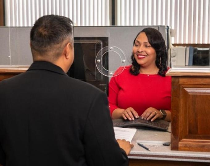 Man with paper standing in front of a smiling customer service representative.