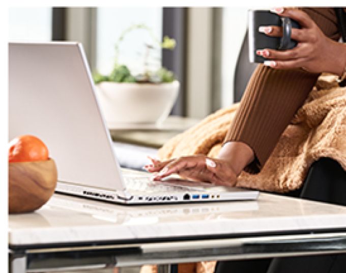 A person wearing a brown ribbed top working on a silver laptop.