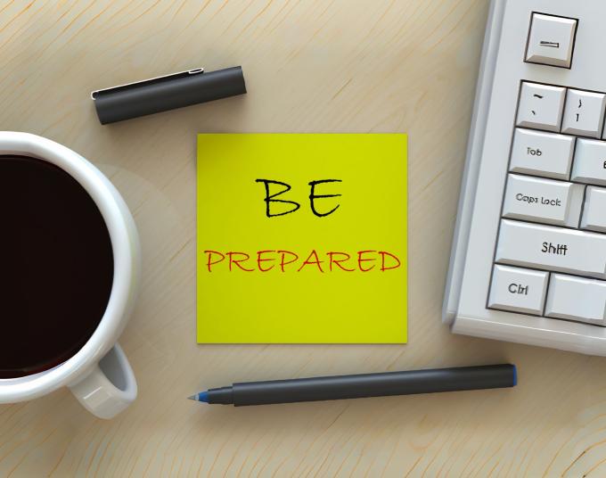 desk with coffee, pen, keyboard and "Be Prepared" note 