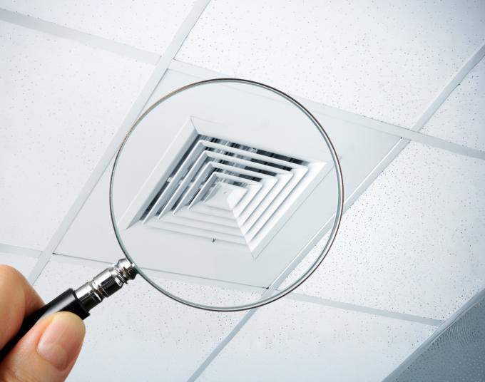 person holding magnifying glass over vent