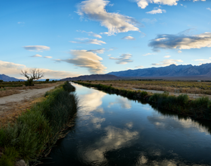Scenic view of the Owens River with vegetation and mountain range landscape in the horizon.