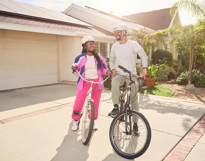 man and woman on bicycles in front of driveway