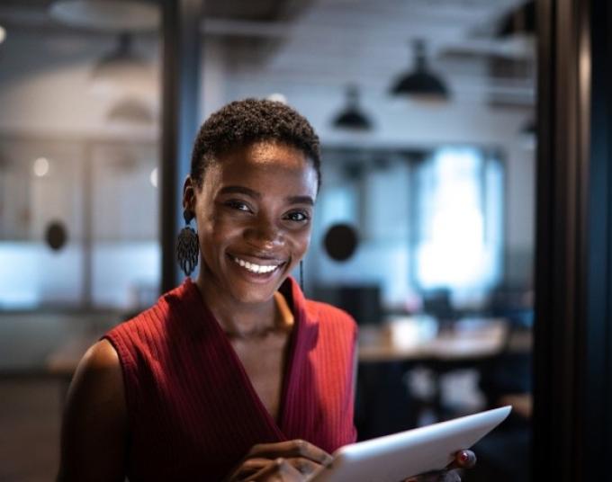person standing in dim office space holding tablet