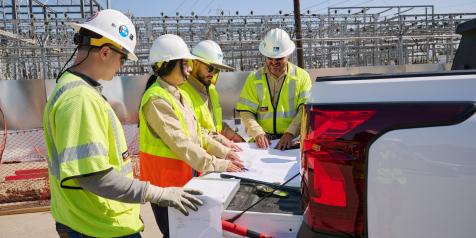 מהנדסי LADWP עם קסדות קשות באתר העבודה מסתכלים על תוכניות