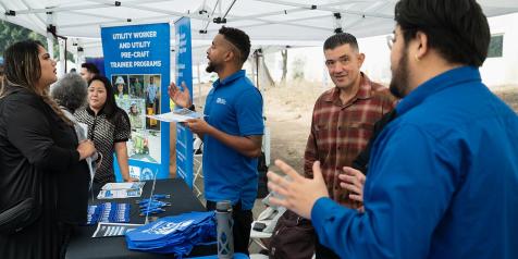 People standing and speaking at an information table.