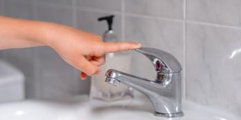 Photo of hand with finger on bathroom faucet handle