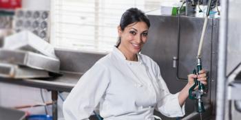 A kitchen worker washes dishes.