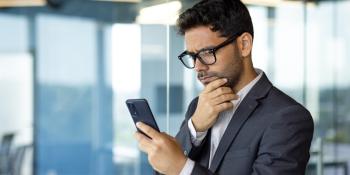 A man in a suit looks at his smartphone.